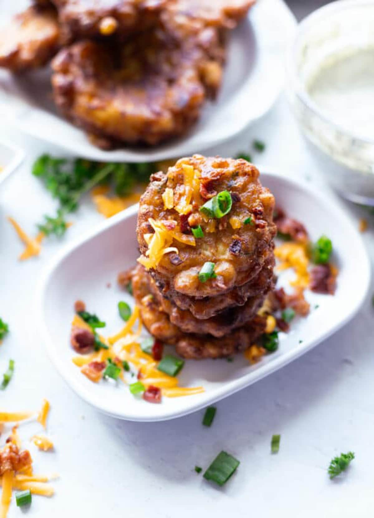 Stacked corn fritter in a white dish. 