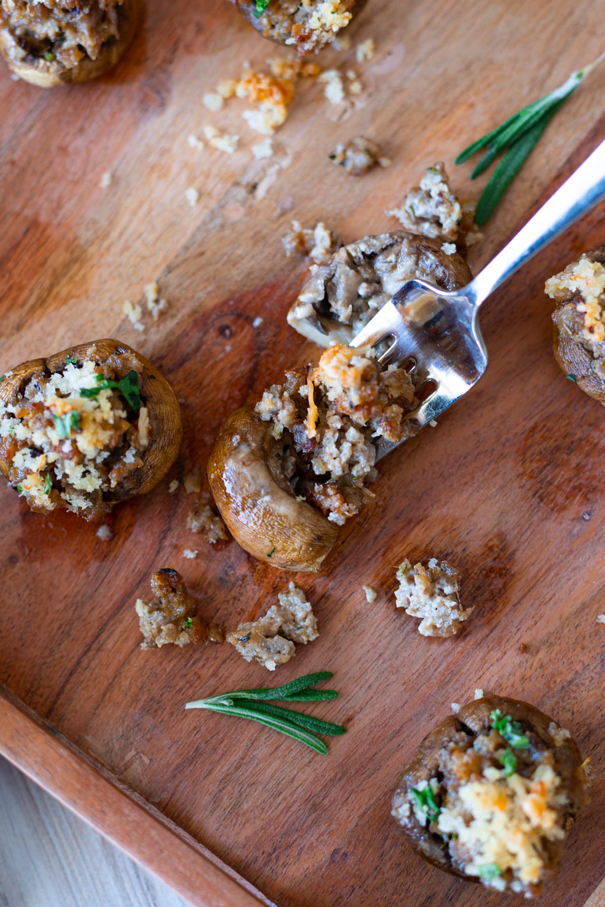 Person using a fork to eat sausage stuffed mushrooms. 