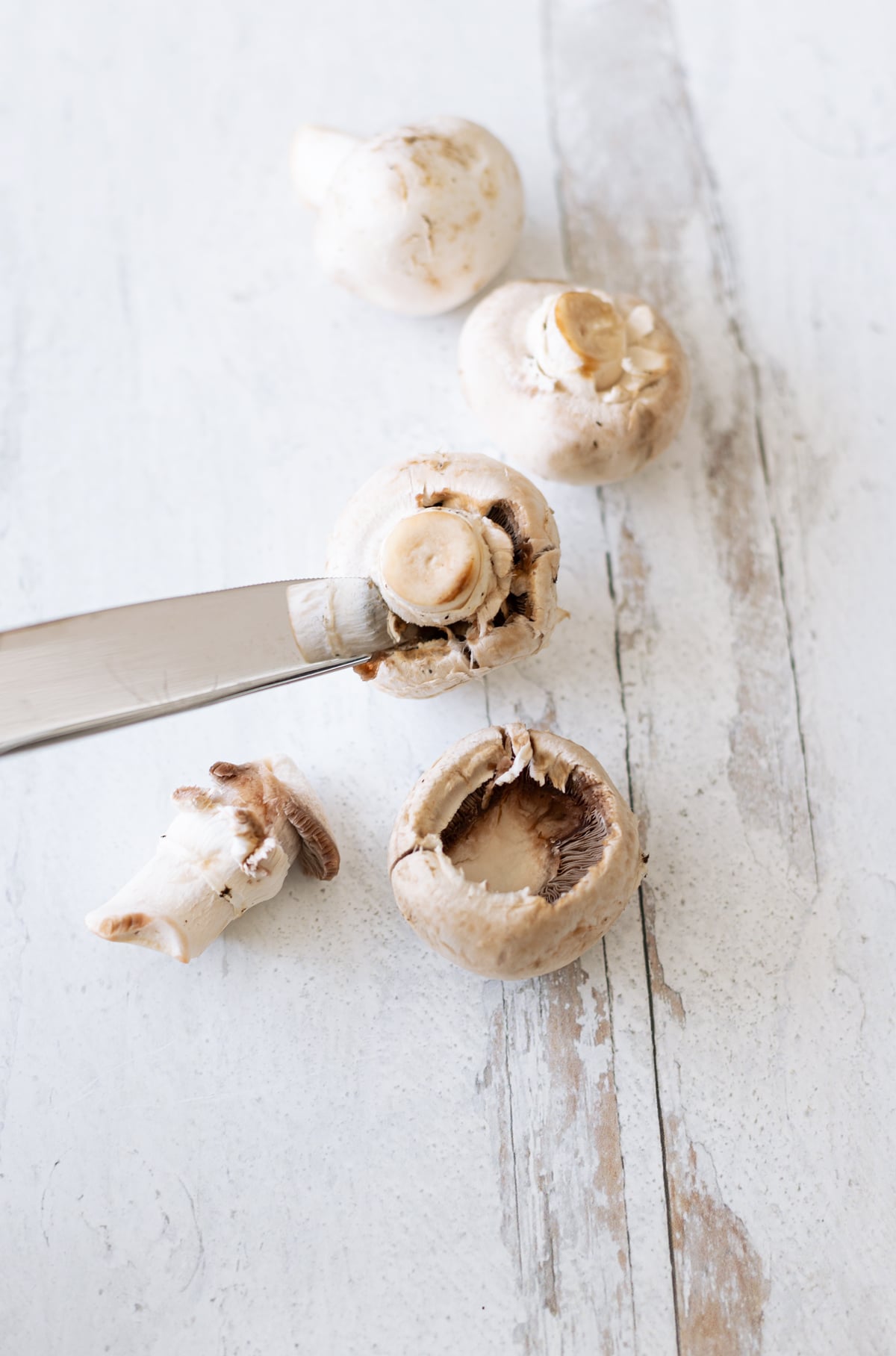 Person removing stem from mushroom. 