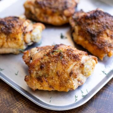 Seasoned baked chicken thigh on a serving dish.