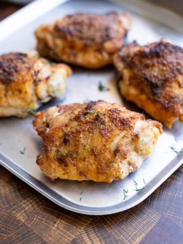 Seasoned baked chicken thigh on a serving dish.