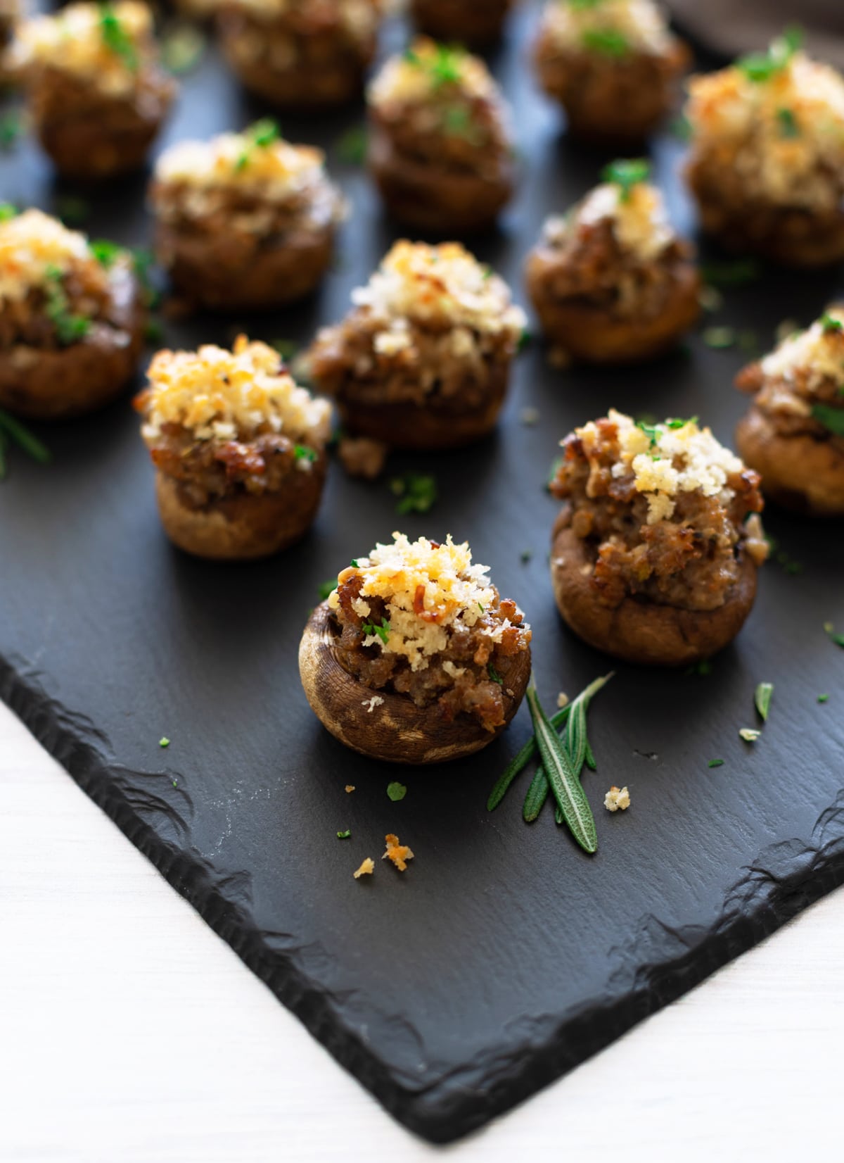 Close up of rows and rows of sausage stuffed mushrooms on a serving platter,