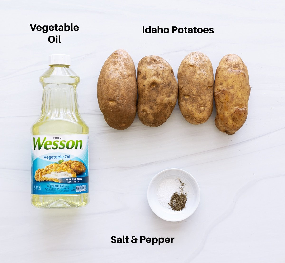 Ingredients on a counter showing potatoes, vegetable oil, salt and pepper.