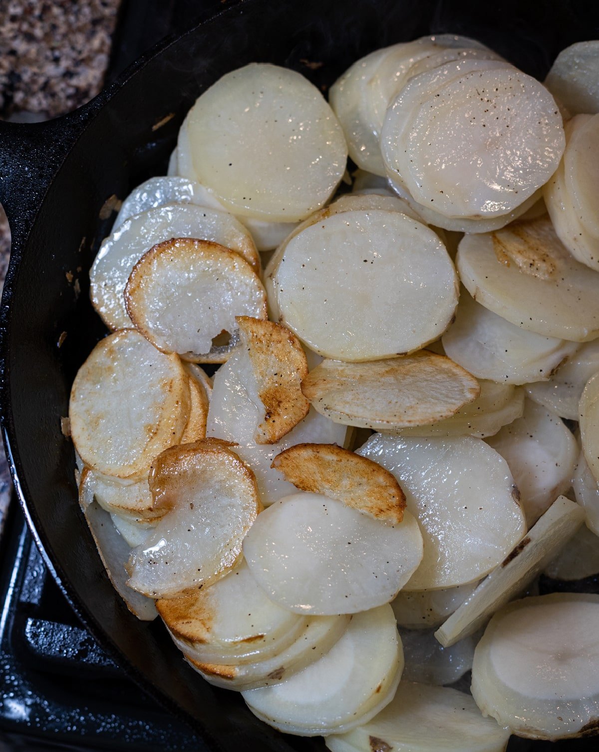 Fried potatoes being made in a skillet.