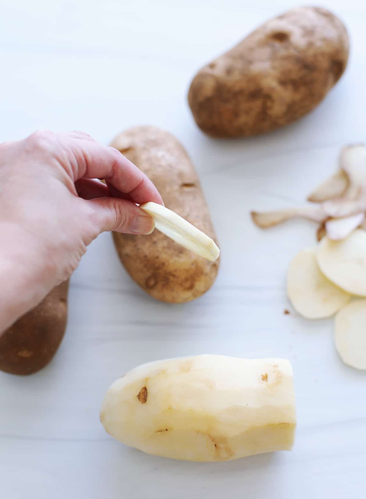 Person showing how thick to slice a potato to fry them.
