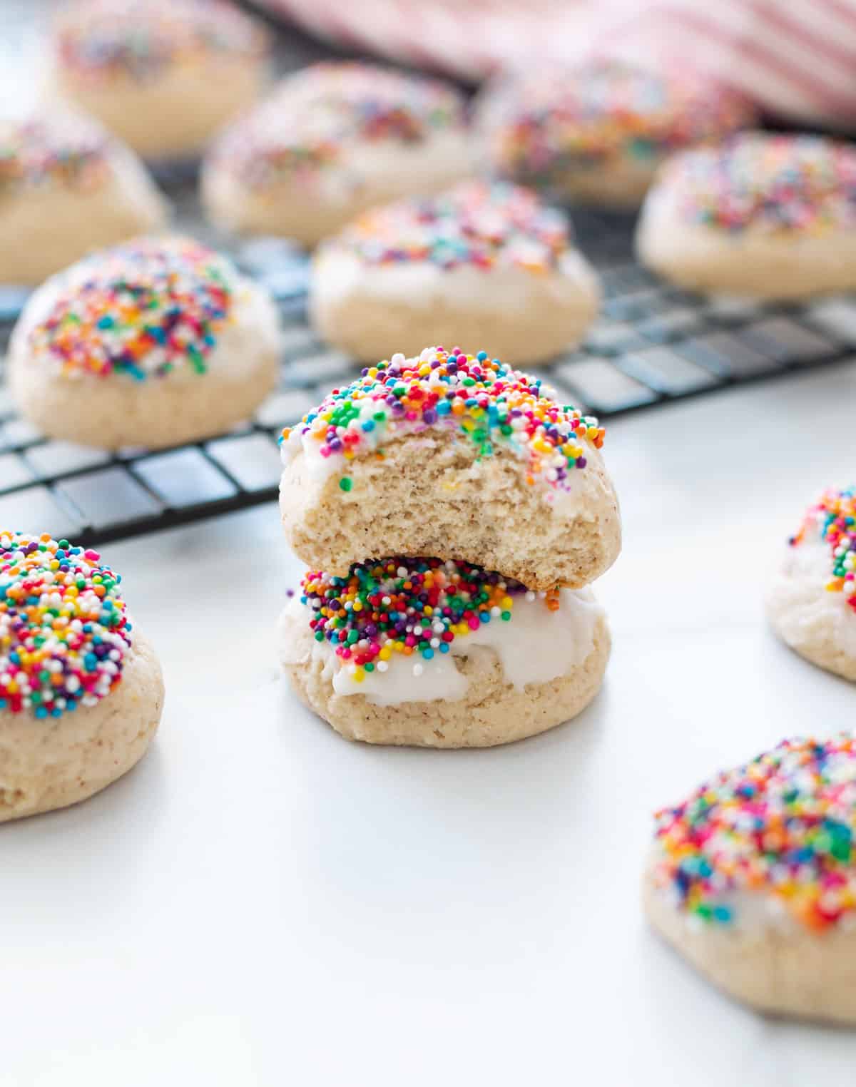 Anise cookie stacked on a counter with a bit taken out of the cookie.