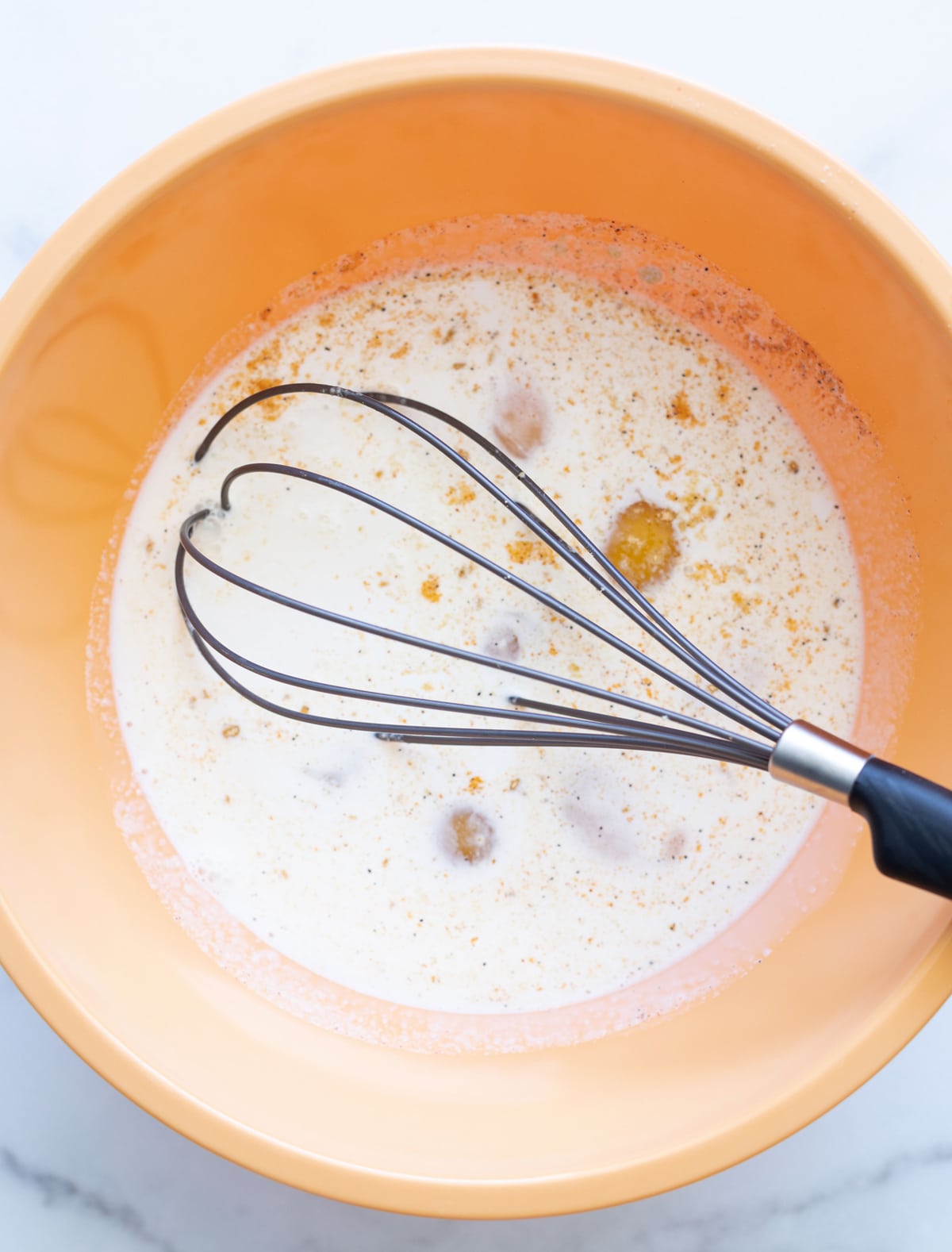 Person mixing eggs with liquid ingredients to make breakfast casserole. 