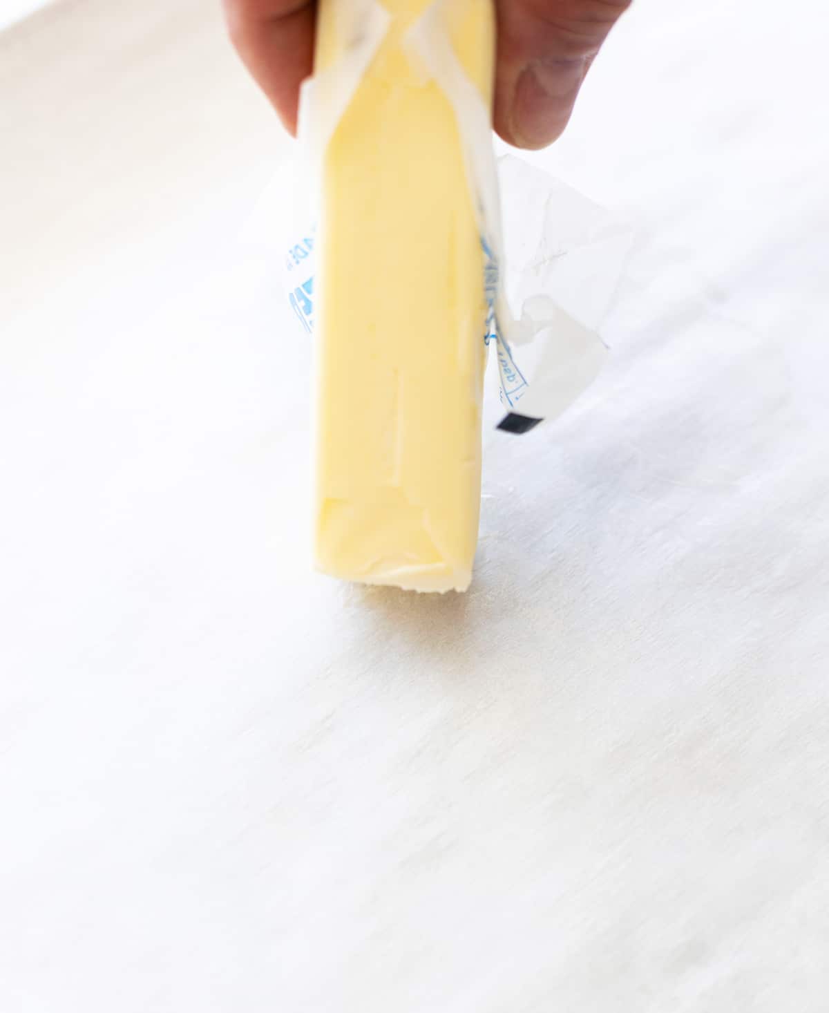 Person taking a stick of butter to coat the baking sheet. 