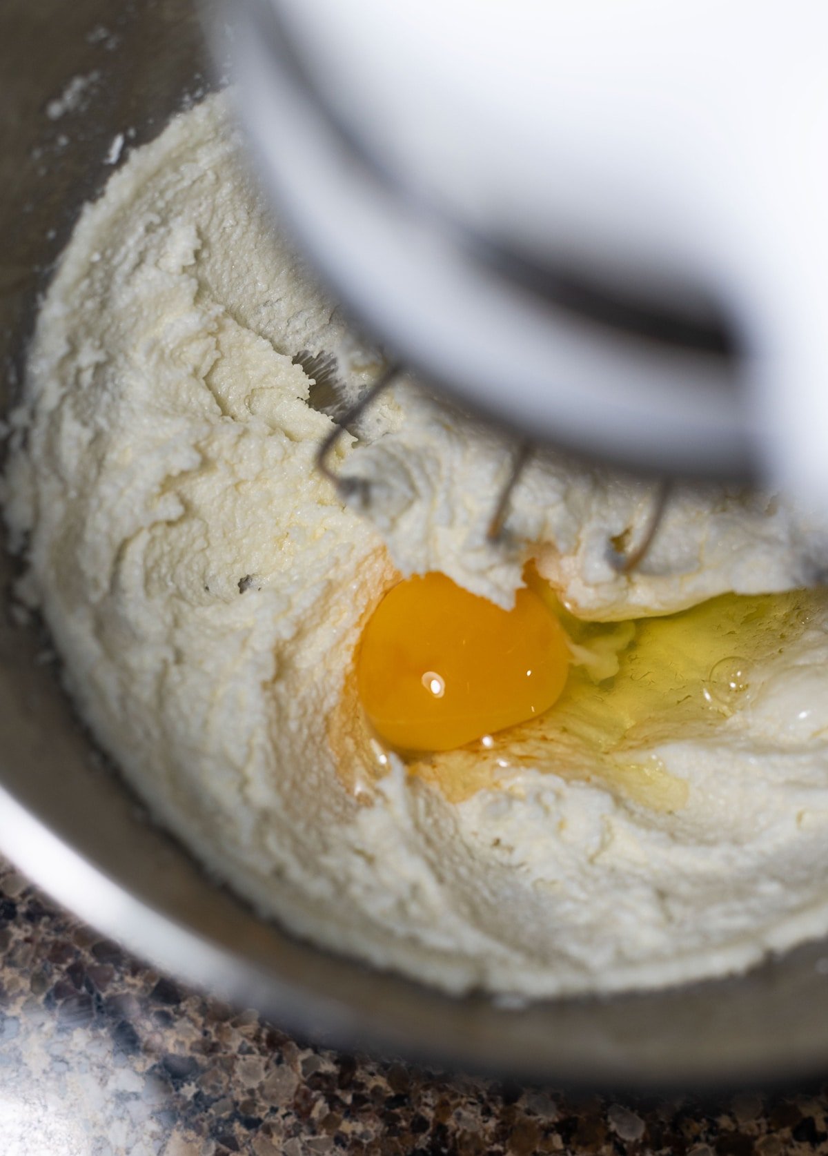 Eggs being added to a mixing bowl with the cookie dough. 