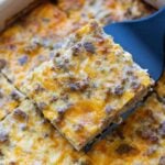 Person serving a piece of breakfast casserole from a dish.