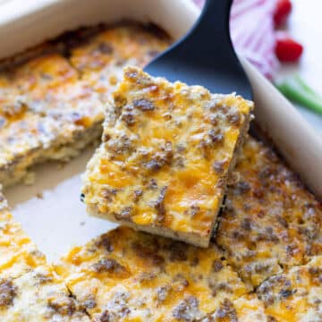 Person serving a piece of hash brown casserole from a dish.