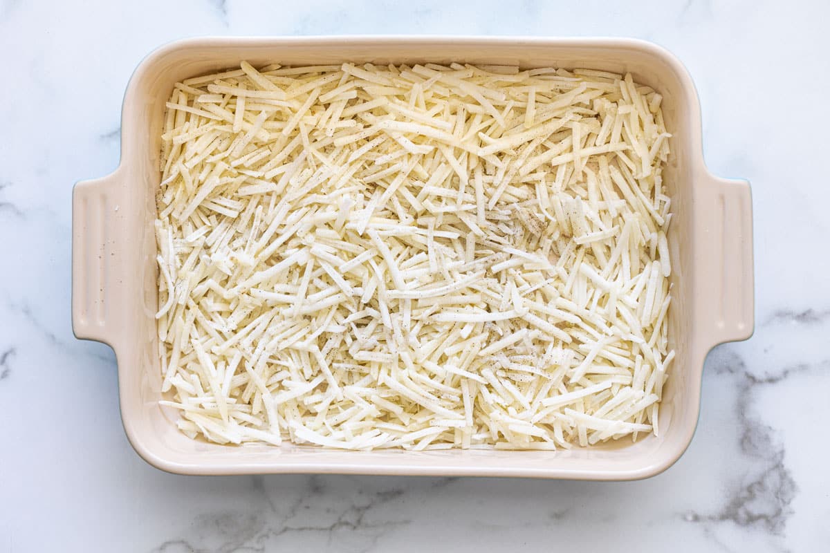 Casserole dish filled with shredded hash browns. 