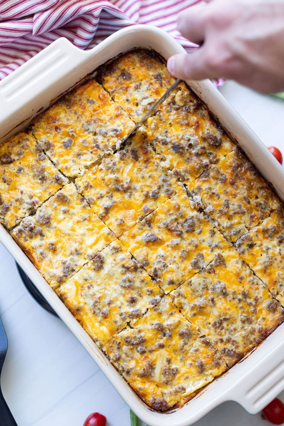 Person slicing hash brown breakfast casserole. 