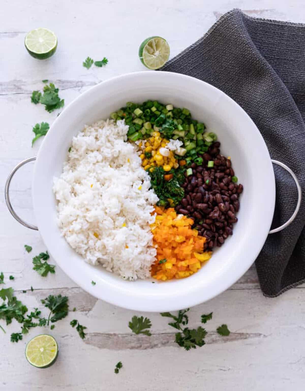 Large bowl filled with rice, black beans, peppers and scallions, and corn.