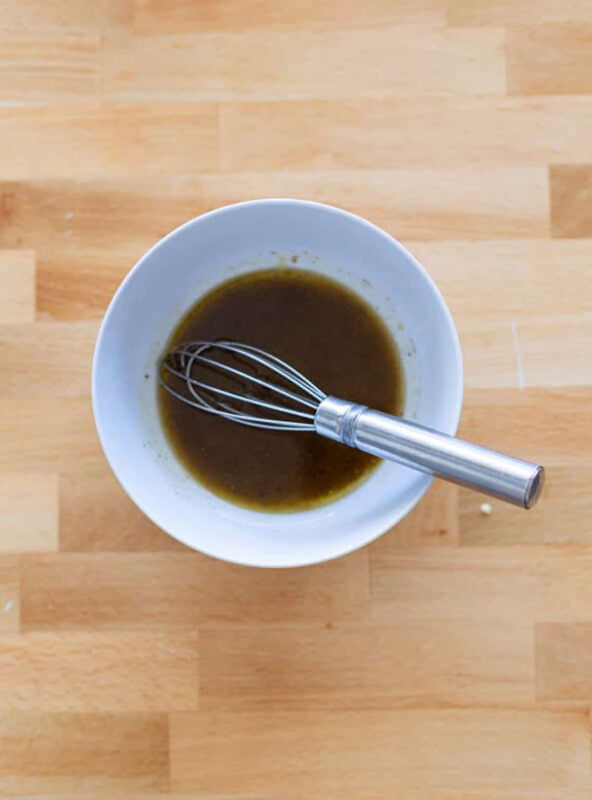 Person whisking dressing in a bowl.