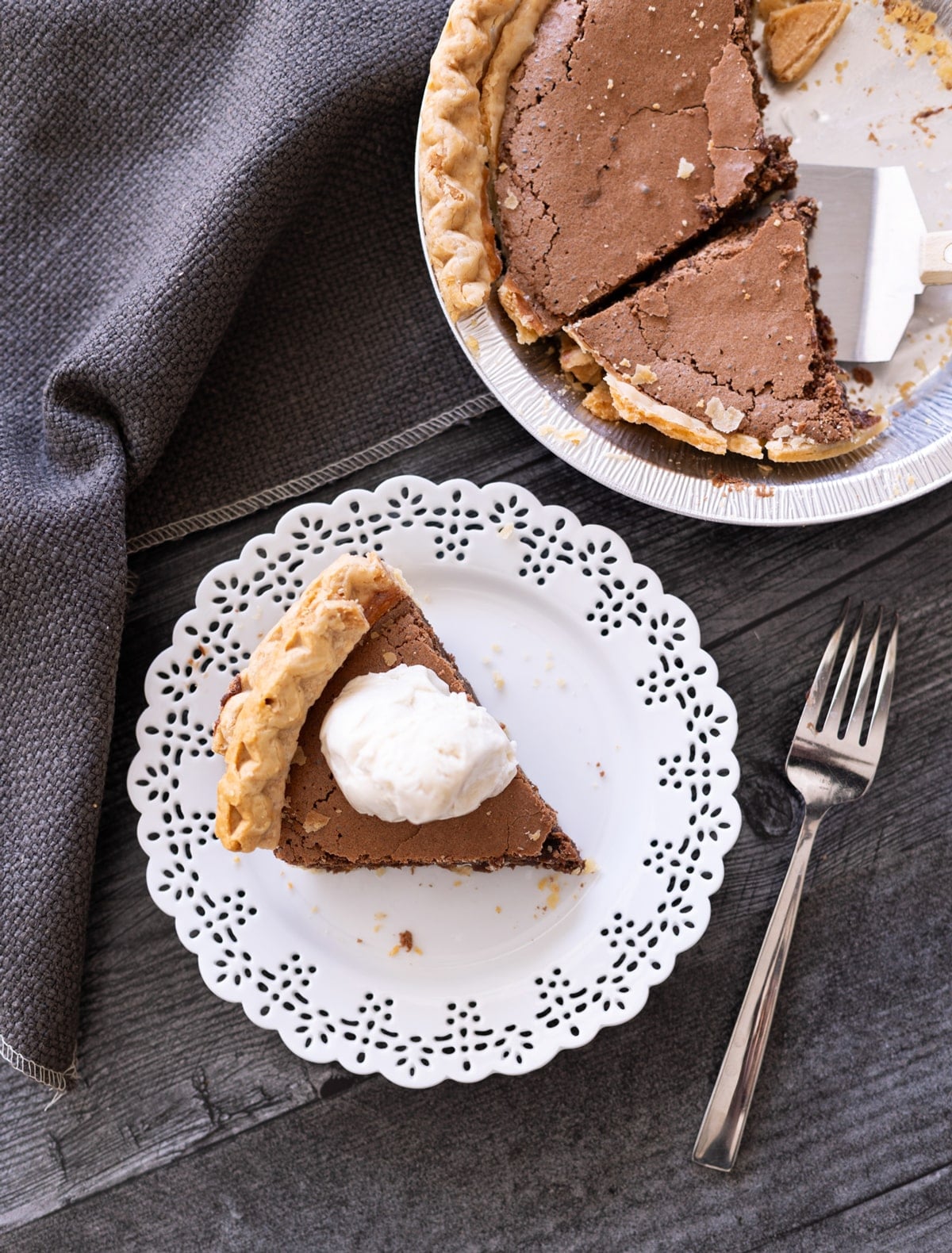 Piece of chocolate pie on a plate with the pie in a baking dish in the background.