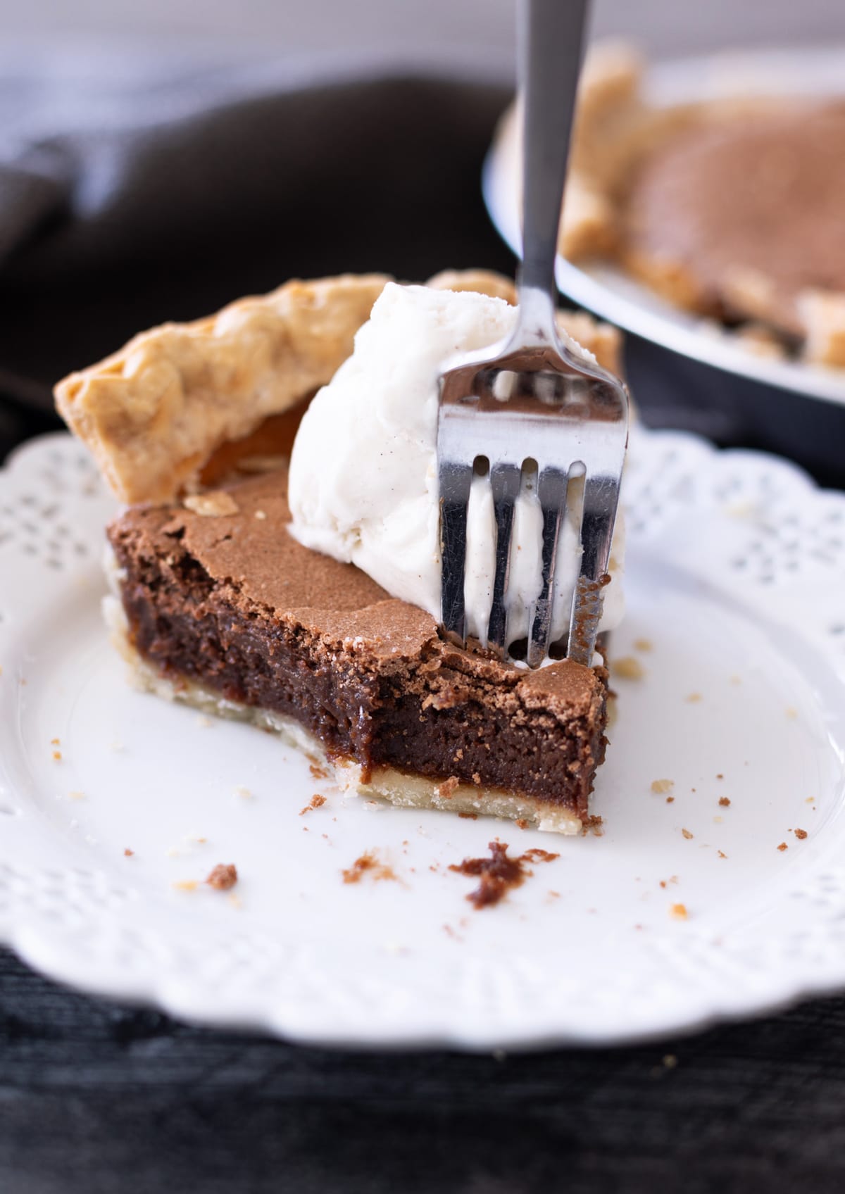 Person using a fork to take a bite out of a chocolate pie.