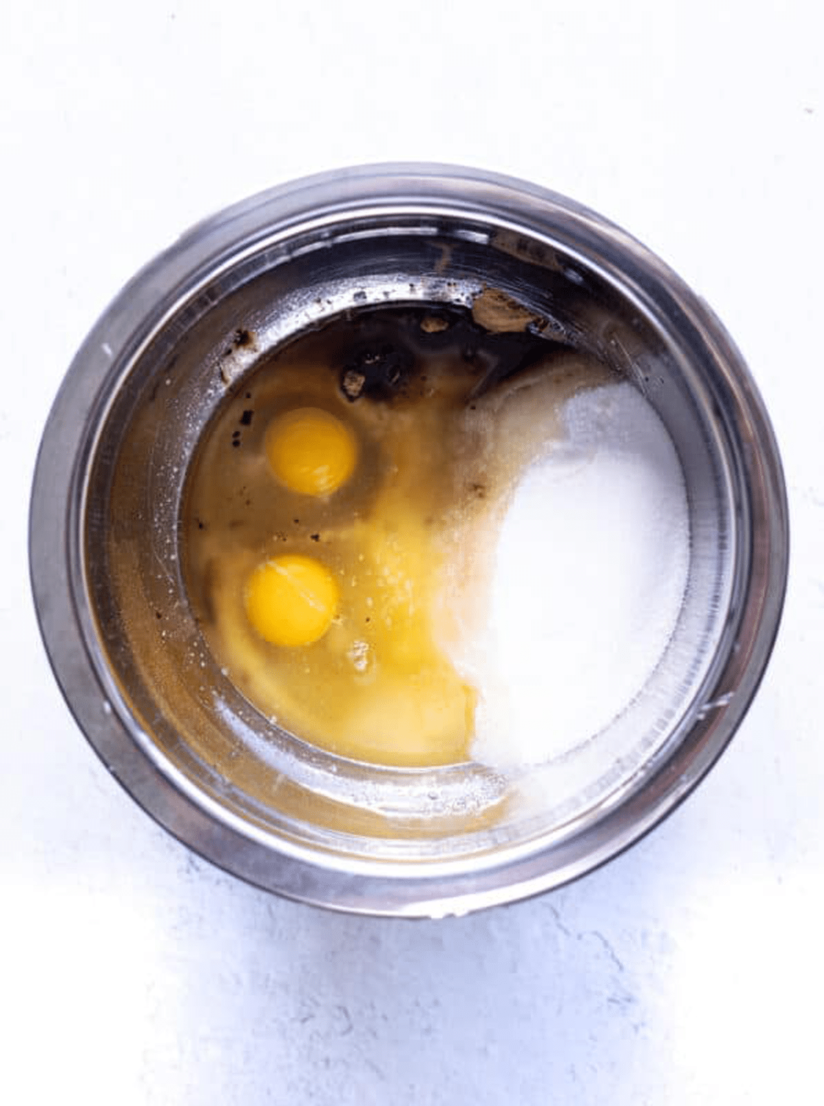 Mixing bowl filled with eggs, sugar, cocoa, and vanilla extract.