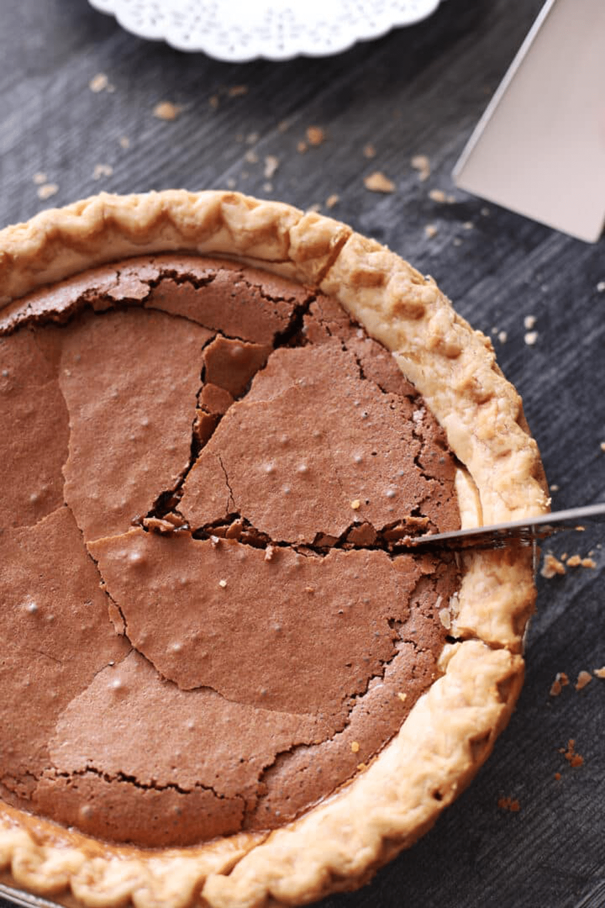 Person slicing a piece of chocolate pie.