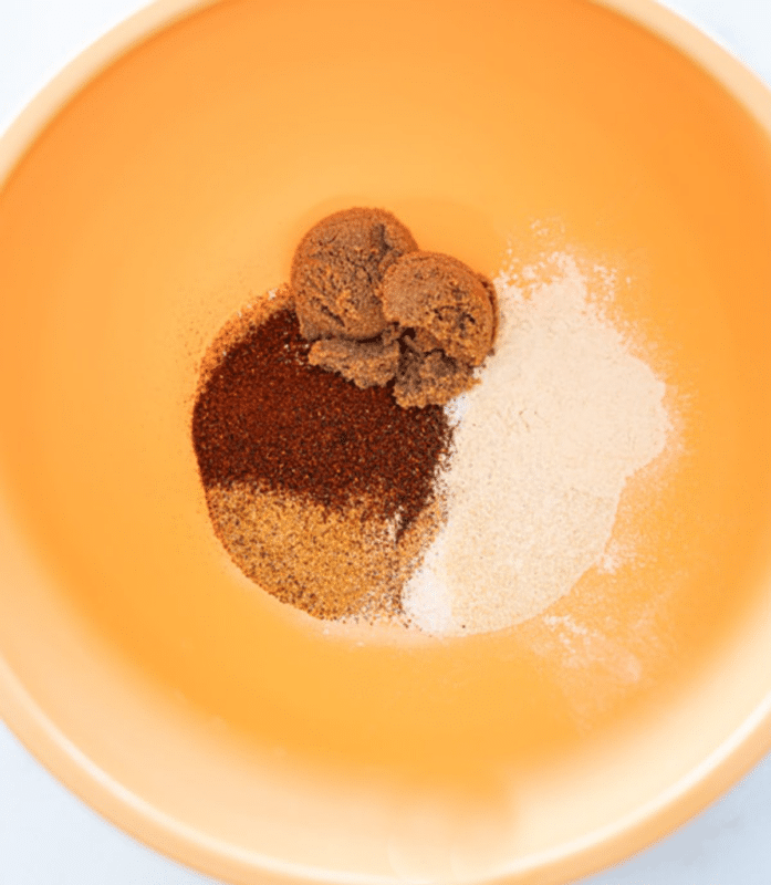 Person adding ingredients to a bowl to make a steak seasoning.