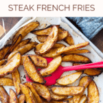 Seasoned steak fries being stirred in a baking dish.