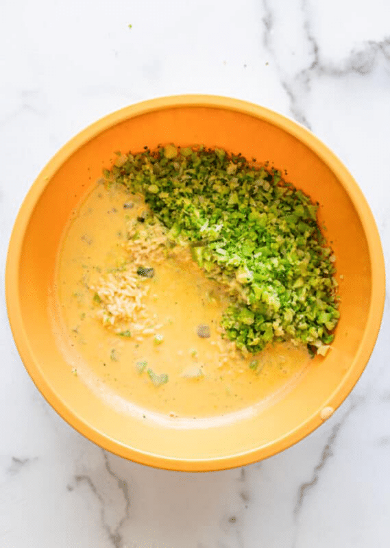Bowl filled with melted cheese sauce and chopped broccoli.