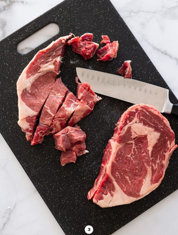 Person cutting steak on a cutting board.
