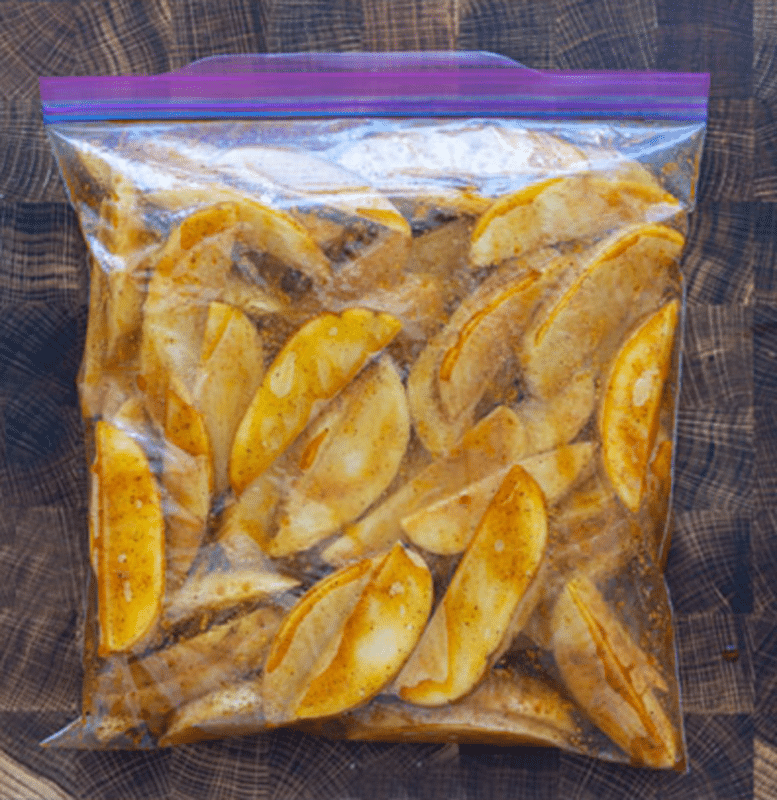 Large plastic bag filled with seasoned steak fries.
