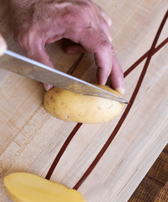 Person cutting a potato in half.