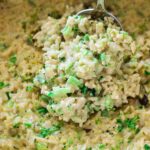 Person serving a spoonful of broccoli rice casserole from a dish.