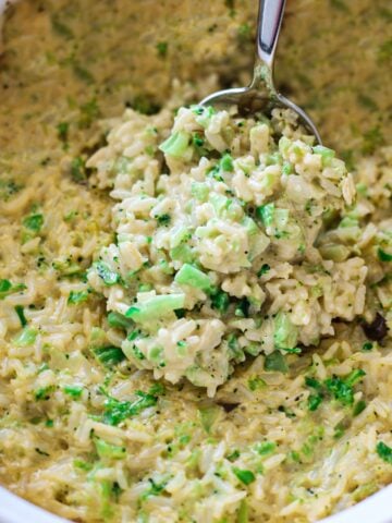 Person serving a spoonful of broccoli rice casserole from a dish.
