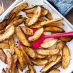Person flipping steak fries in a baking dish.